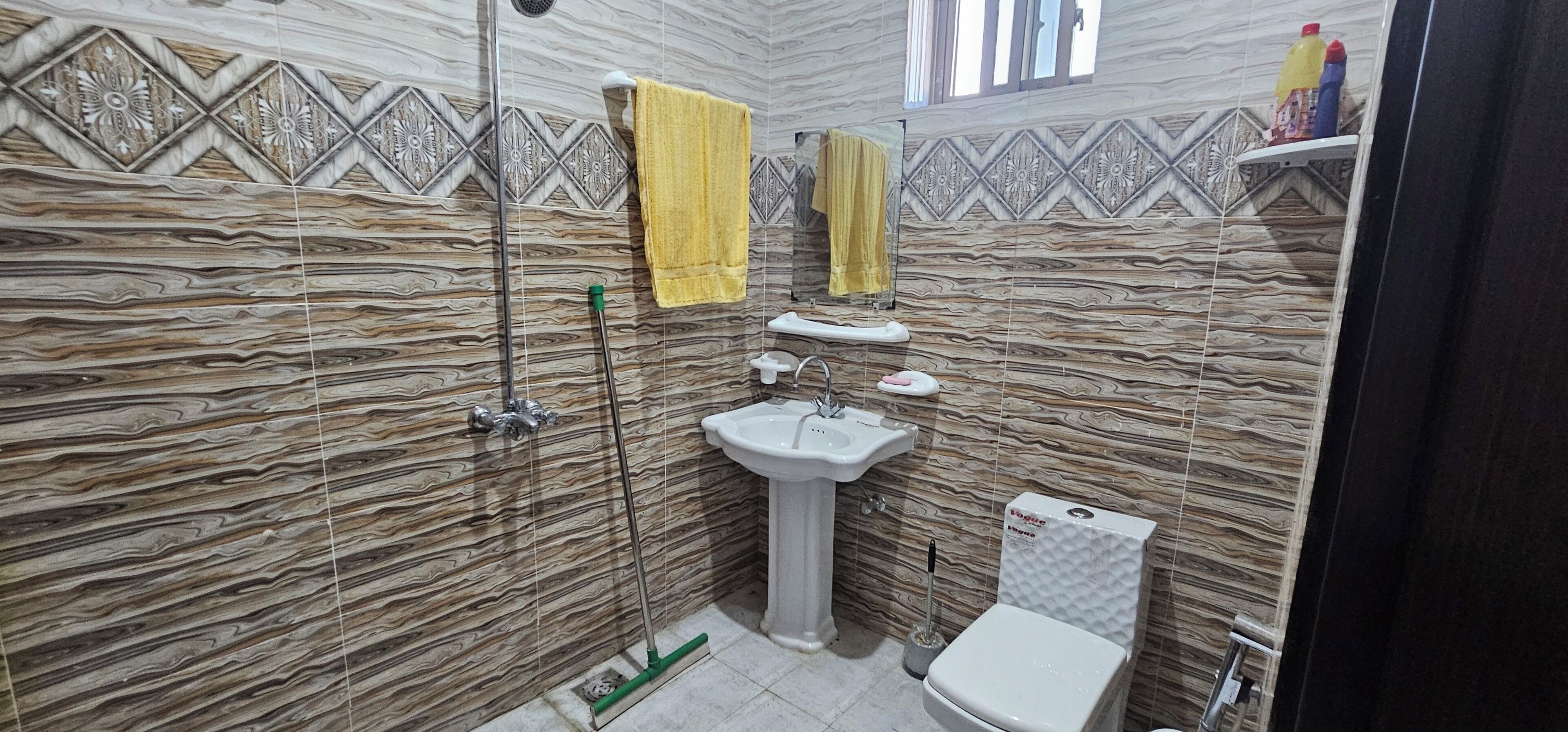 Ein Badezimmer mit Dusche, Waschbecken, Toilette und dekorativen Fliesen.