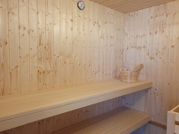 A wooden sauna with a bench and a wooden bucket.