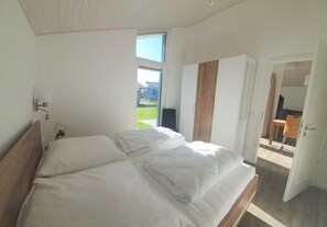 Relax in a serene bedroom with a large bed, window, and stylish wardrobe.