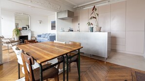A modern kitchen with a wooden dining table, white cabinetry, and a herringbone-patterned floor. - 2 BD lovely APT facing Canal St Martin sleeps 6! (Paris)