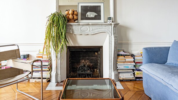 A living room with a fireplace, a blue sofa, a glass coffee table, and a white-framed mirror above the fireplace. - 2 BD lovely APT facing Canal St Martin sleeps 6! (Paris)