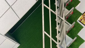 A modern building with a green artificial lawn and a metal staircase. - Hotel Neki & Restaurant (Meerut)