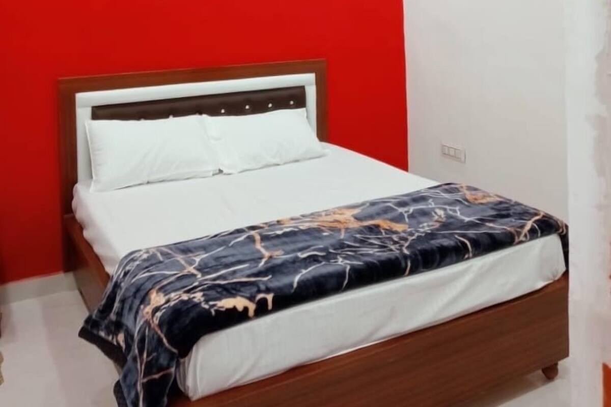 A bedroom with a red wall, a wooden bed frame, and a ceiling fan.