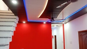 A staircase with a red wall and white steps, leading to a hallway with a ceiling fan and recessed lighting. - Hotel Neki & Restaurant (Meerut)