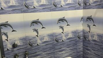 A bathroom with dolphin-themed tiles, a toilet, and a shower.