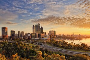 A city skyline with modern buildings, a river, and a highway.
