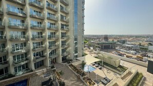 A high-rise building with multiple balconies and a rooftop pool area. - Modern Studio in Virdis Damac Hills 2 (Dubai)