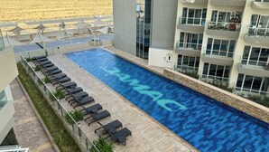 A rooftop swimming pool with lounge chairs and a view of the desert. - Modern Studio in Virdis Damac Hills 2 (Dubai)