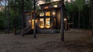 A cabin with a staircase leading to a deck, surrounded by trees. - Office Desk, Deck, Hot Tub, Fire Pit, Pets, Lost in Nature (Broken Bow)