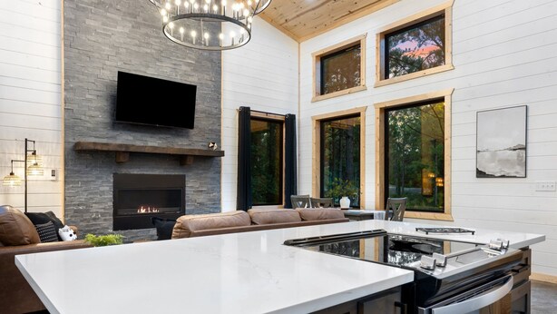A modern kitchen with a large island, a built-in oven, and a flat-screen TV above the fireplace. - Office Desk, Deck, Hot Tub, Fire Pit, Pets, Lost in Nature (Broken Bow)