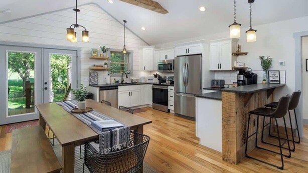 A modern kitchen with white cabinetry, stainless steel appliances, and a wooden island. - Birdsong Cottage | Gorgeous Lake Junaluska Retreat (Waynesville)