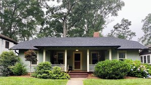 A single-story house with a front porch, a central door, and a small front yard with grass and shrubs. - Bohemian Paradise | Near Downtown | Monthly Stays! (Asheville)