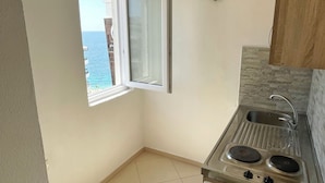 A small kitchen with a window, a sink, and a stove. - Fenix Apartments (Bar)