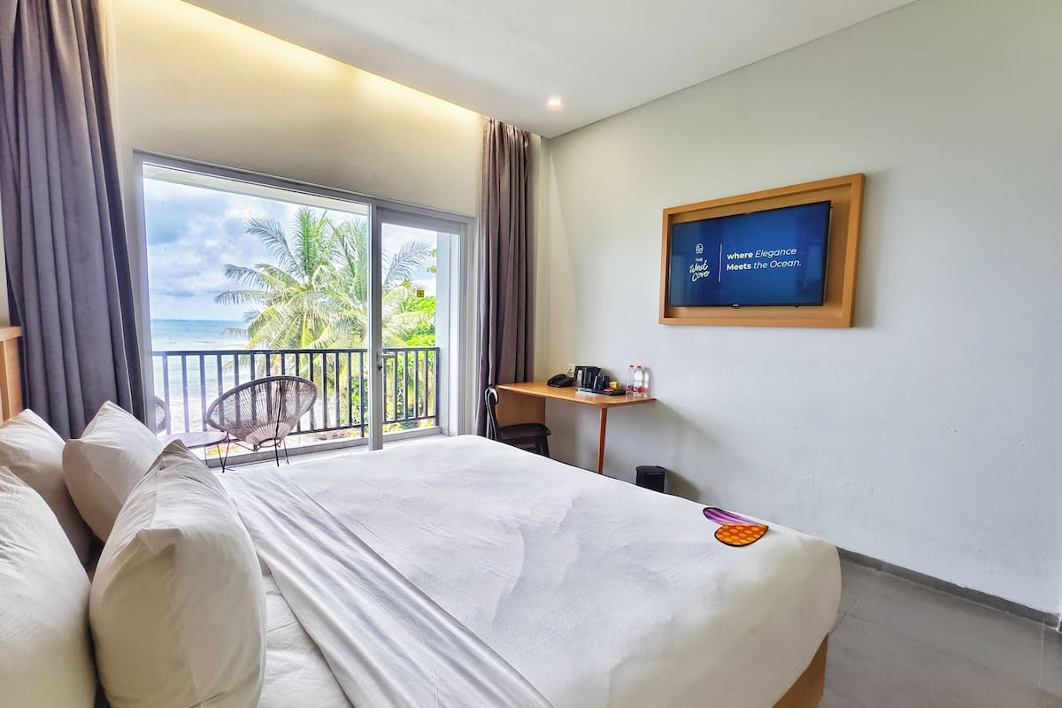 A hotel room with a bed, a desk, a chair, and a view of the ocean.