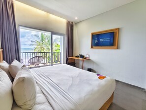 A hotel room with a bed, a desk, a chair, and a view of the ocean.