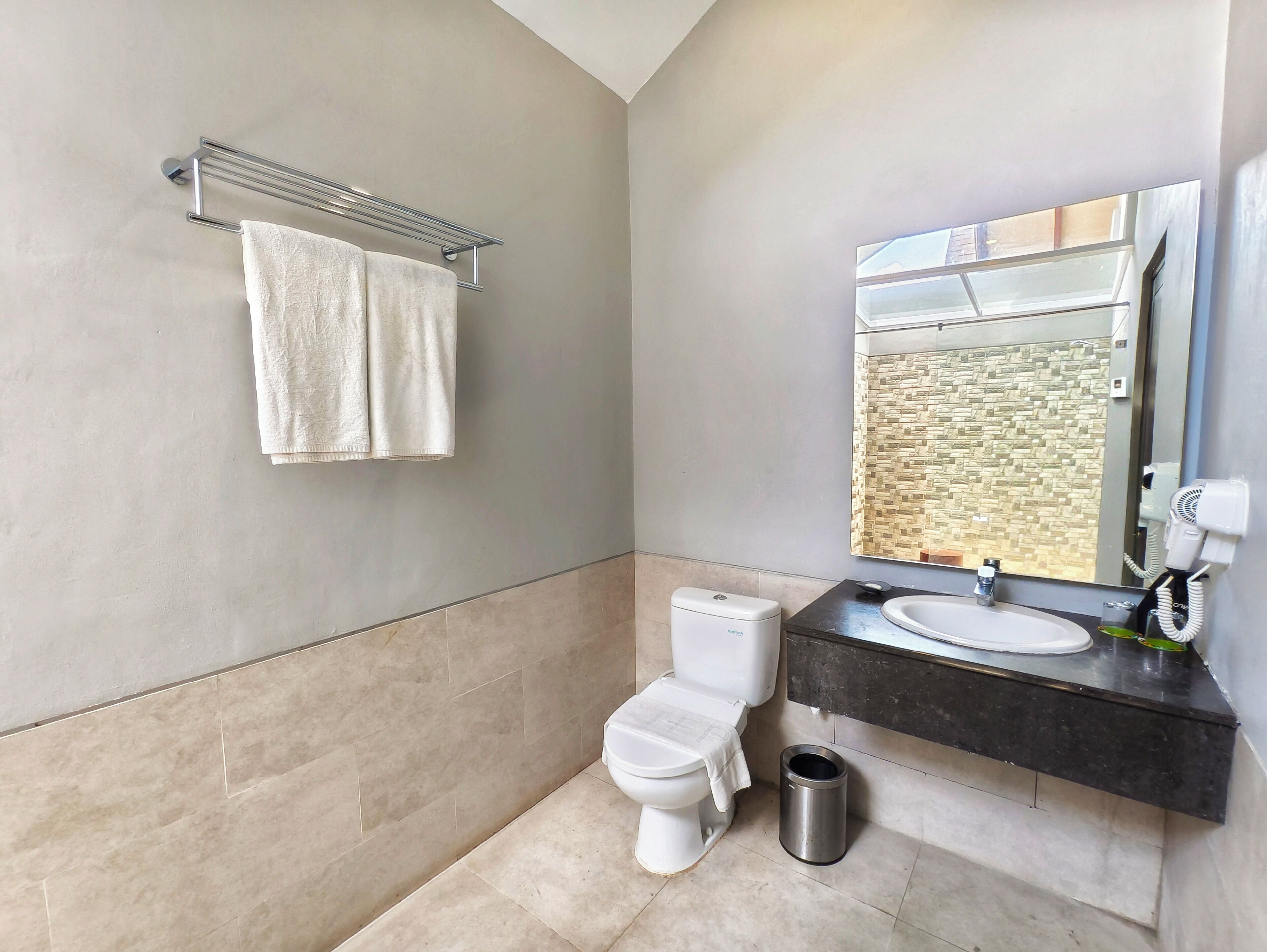 Ein modernes Badezimmer mit Toilette, Waschbecken und Spiegel.