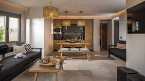 A modern living room with a sofa, a dining table, and a kitchen area.