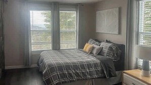 Ein Schlafzimmer mit einem Bett, einem Nachttisch und einem Fenster mit Jalousien.