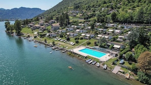 A lakeside resort with a swimming pool, docked boats, and hillside houses. - Direkt am See mit Terrasse (Tre Capitelli)