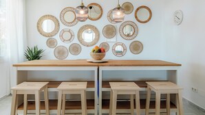 Une cuisine moderne avec un îlot central en bois, six tabourets et divers miroirs décoratifs accrochés au mur.