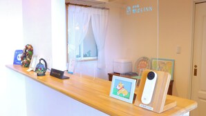 A reception desk with a framed picture of a dog, a sign reading "RECEPTION", and a camera on the counter.