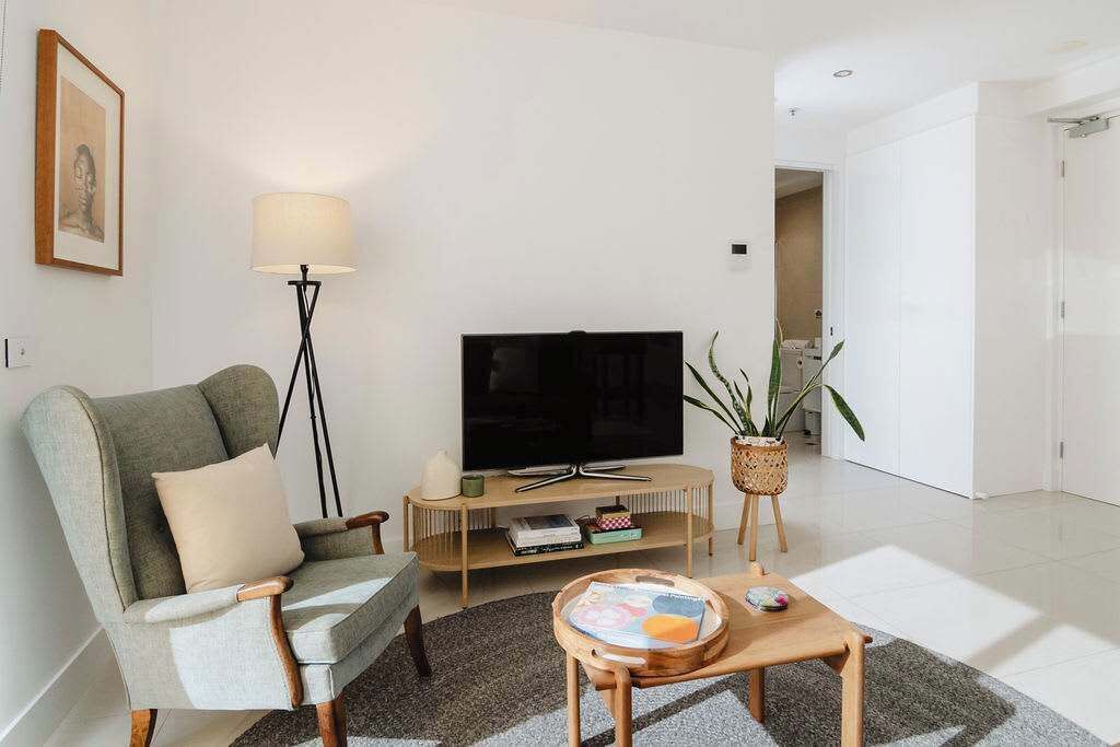 Een woonkamer met een bank, een televisie, een lamp, een salontafel en een plant.