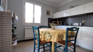 Une cuisine de taille réduite comprenant une table à manger, des chaises et un radiateur.