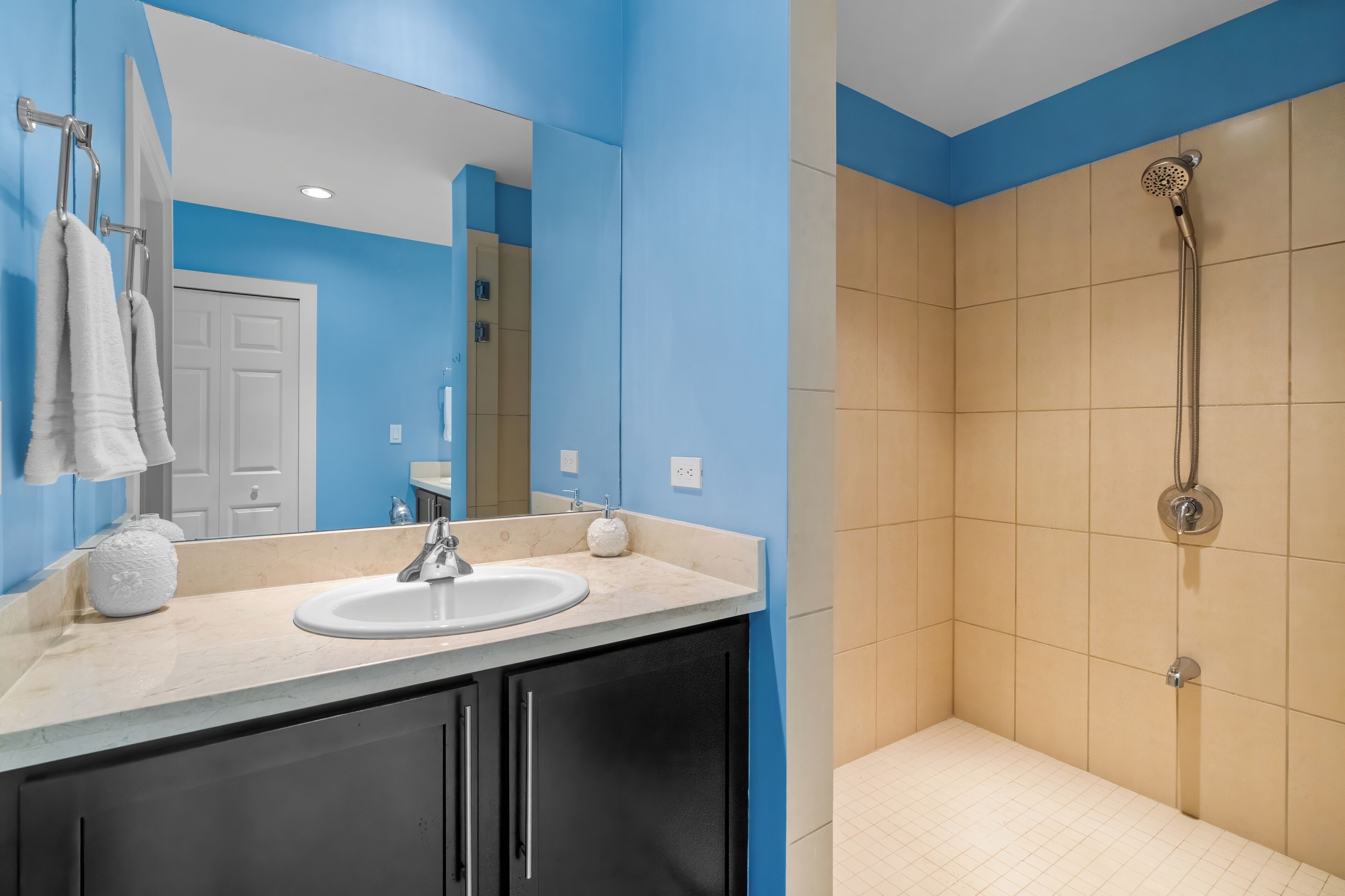 A bathroom with a sink, mirror, and shower.