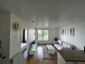 Relax in this serene living room with a large window, comfortable sofa, and stylish coffee table.