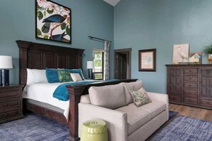 Une chambre à coucher avec un lit, un canapé, une commode et un tableau au mur.