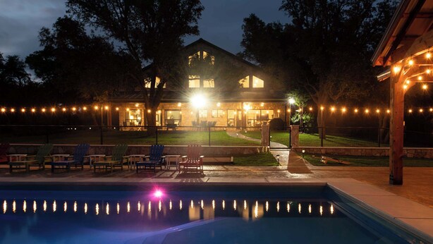 A house with a swimming pool, outdoor seating, and string lights. - Luxury in Wimberley | Pool+Pickleball+Party Barn (Wimberley)