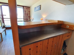 Una cocina con armarios de madera, una encimera y una ventana con cortinas.