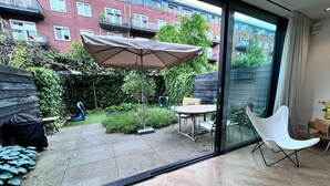 A modern apartment with a patio area featuring a table, chairs, and a large umbrella. - Heerlijk Ruim Familie Appartement Vlakbij de Jordaan (Amsterdam)