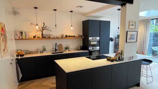 A modern kitchen with black cabinetry, a central island, and pendant lighting. - Heerlijk Ruim Familie Appartement Vlakbij de Jordaan (Amsterdam)