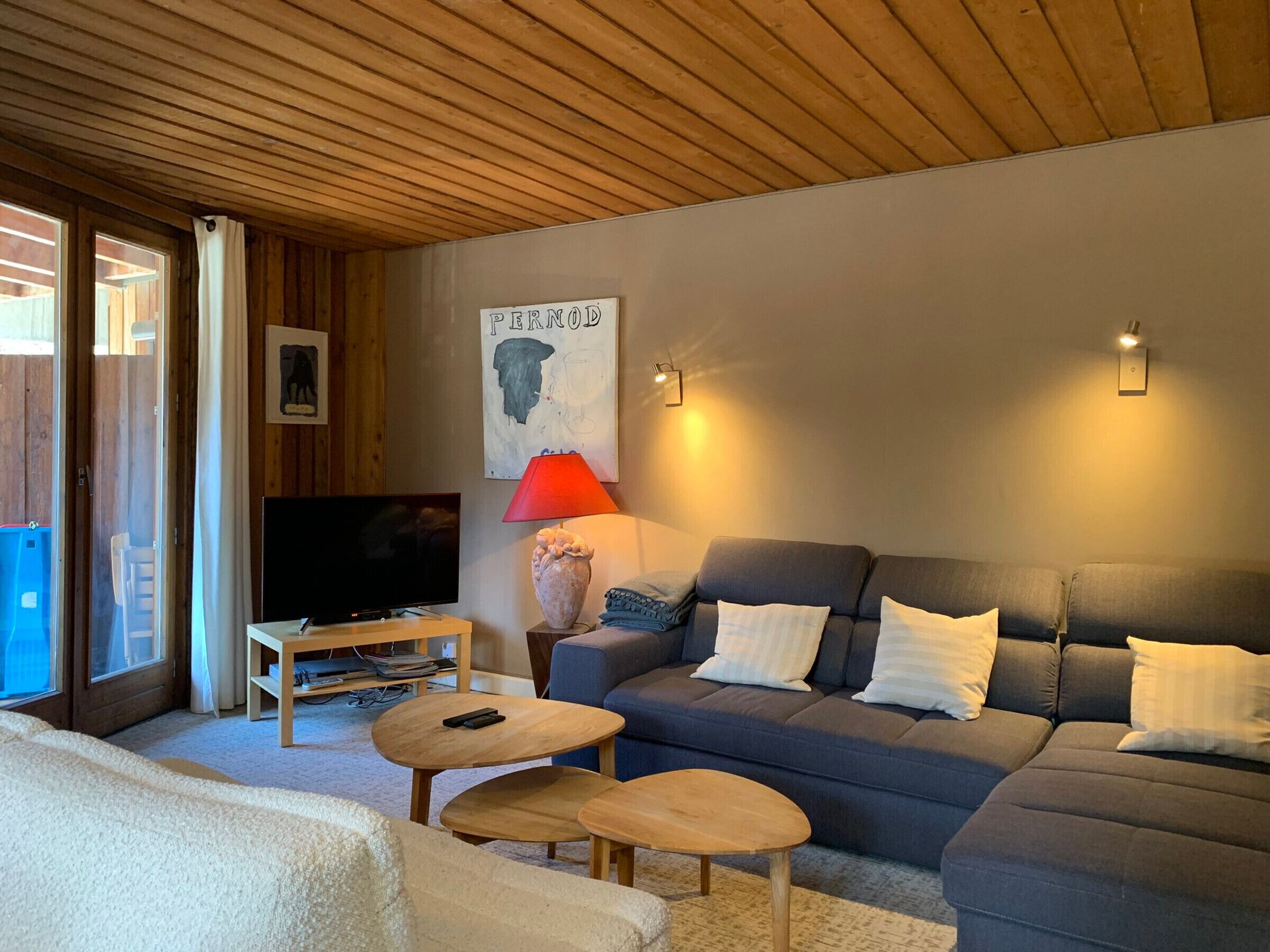 A living room with a sofa, two small tables, a TV, and a lamp.