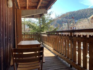 Eine Holzterrasse mit Tisch und Stühlen mit Blick auf eine gebirgige Landschaft.