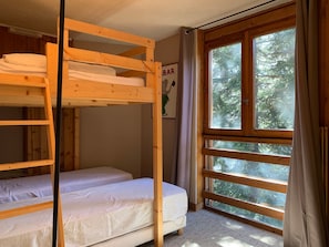 A bunk bed room with a window, a 'BAR' sign, and a poster on the wall.