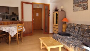 A cozy living room with a sofa, a small table, and a dining area with chairs and a table. - Apartment 6 pers, South Terrace, Pra-Loup (Pra-Loup)