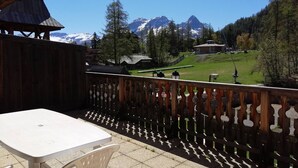 A balcony with a view of a mountain range, a wooden fence, and a table with chairs. - Apartment 6 pers, South Terrace, Pra-Loup (Pra-Loup)