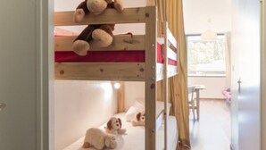 Una cama litera con un peluche de mono en la parte superior y dos peluches de perro en la inferior.