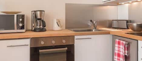 A modern kitchen with a microwave, coffee maker, toaster, sink, and oven.