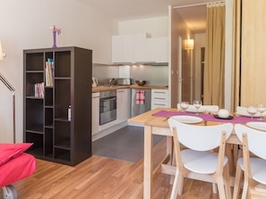 A compact kitchen with white cabinets, a built-in oven, and a dining area with a table set for two.