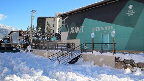 Zona nevada con un edificio que tiene un cartel grande que dice "ARAVET" y "BIENVENUE".