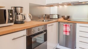 Una cocina moderna con electrodomésticos de acero inoxidable, encimera de madera y armarios blancos.