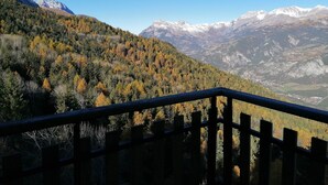 A mountainous landscape with autumn foliage and snow-capped peaks in the distance.