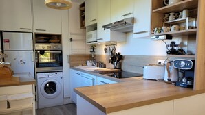 A compact kitchen with a built-in oven, microwave, and washing machine.