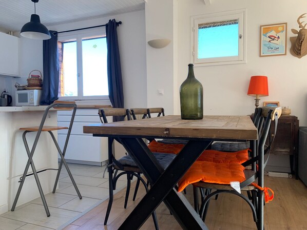 A compact kitchen with a dining table, chairs, and a hanging light fixture.