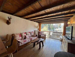 Relax in this inviting space with a sofa, coffee table, and TV, surrounded by a view of the outdoors.