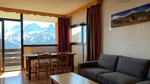 Una sala de estar con un sofá, una mesa de madera y una mesa de comedor con sillas.