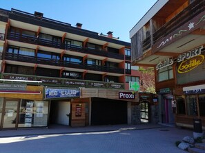 Ein mehrgeschossiges Gebäude mit Gesch äften im Erdgeschoss, darunter eine Diskothek, eine Apotheke und ein Sportgeschäft.